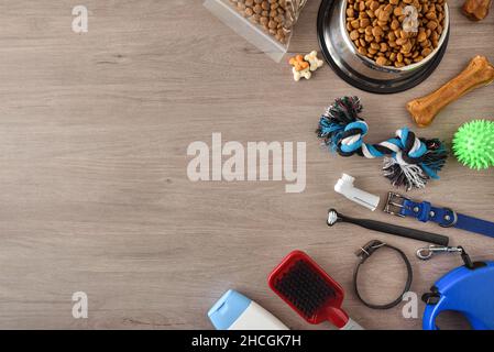 Food and accessories for walk, play and body care for the dog on wooden table. Top view. Horizontal composition. Stock Photo