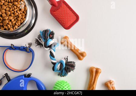 Food and accessories for walk, play and body care for the dog on white table. Top view. Horizontal composition. Stock Photo