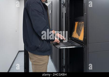 Close up on Data Center Engineer hands Using keyboard on a supercomputer Server Room Specialist Facility with Male System Administrator Working with Stock Photo
