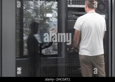 Technicians team updating hardware inspecting system performance in super computer server room or cryptocurrency mining farm. Stock Photo