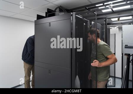 Technicians team updating hardware inspecting system performance in super computer server room or cryptocurrency mining farm. Stock Photo