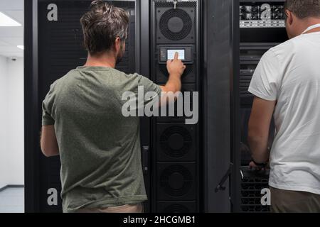Data Center Engineer Using Laptop Computer. Server Room Specialist Facility with Korean Male System Administrator Working with Data Protection Network Stock Photo