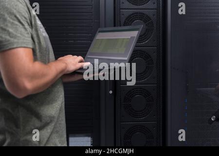 Data Center Engineer Using Laptop Computer. Server Room Specialist Facility with Korean Male System Administrator Working with Data Protection Network Stock Photo
