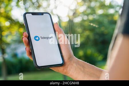 Woman hand holding iphone Xs with logo of Telegram application. Telegram app icon. Telegram is an online social media network. Social media app Stock Photo