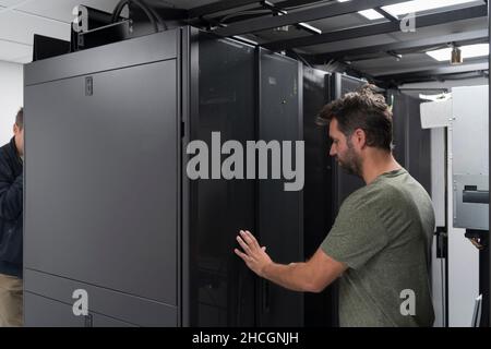 Technicians team updating hardware inspecting system performance in super computer server room or cryptocurrency mining farm. Stock Photo