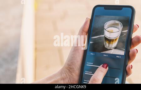 Photo edit with mobile phone and smart app. Woman adjusting sliders. Image editing, manipulation, improvement or enhancement with smartphone. Adding f Stock Photo
