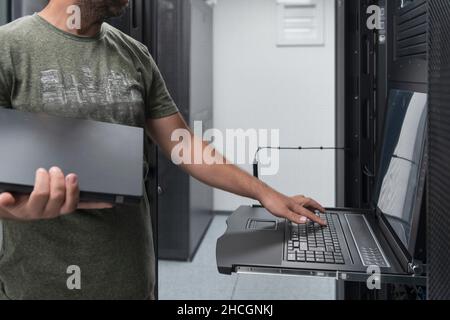 Close up on Data Center Engineer hands Using keyboard on a supercomputer Server Room Specialist Facility with Male System Administrator Working with Stock Photo