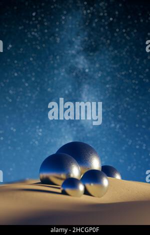 Abstract 3D background of metal spheres on sand against stars of the milky way in the sky. Selective focus on the middle sphere. Epic scifi landscape. Stock Photo