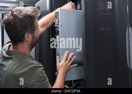 IT engineer working In the server room or data center The technician puts in a rack a new server of corporate business mainframe supercomputer or Stock Photo