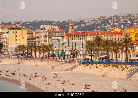 People on the beach of the Mediterranean Sea bathing in front of the Promenade des Anglais. Panoramic vue over the old town of Nice, France. Nice, Fra Stock Photo