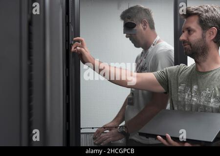 Technicians team updating hardware inspecting system performance in super computer server room or cryptocurrency mining farm. Stock Photo