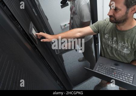 Technicians team updating hardware inspecting system performance in super computer server room or cryptocurrency mining farm. Stock Photo
