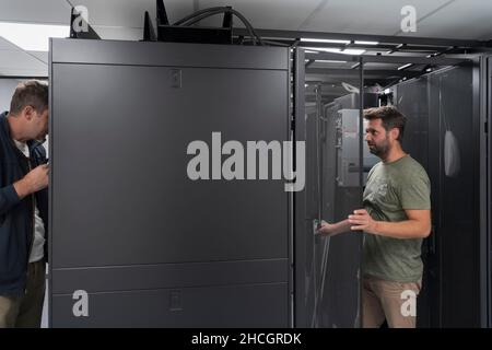 Technicians team updating hardware inspecting system performance in super computer server room or cryptocurrency mining farm. Stock Photo