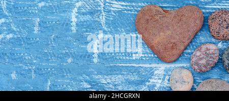 Sea pebbles and seashells on the table. A pyramid of sea stones on a blue background. Stock Photo