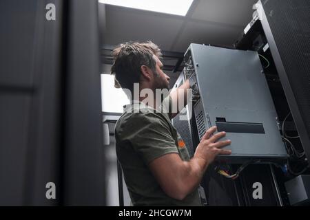IT engineer working In the server room or data center The technician puts in a rack a new server of corporate business mainframe supercomputer or Stock Photo