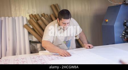 Logistic printing technician worker controls and arranges the printed material on the production line in digital printshop office. Industrial working Stock Photo