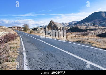 Asphalt countrysde road in Cappadocia, Turkey with no cars around and rock formations ion the background in a sunny day. Travel and road trip in Turke Stock Photo