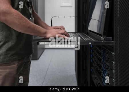 Close up on Data Center Engineer hands Using keyboard on a supercomputer Server Room Specialist Facility with Male System Administrator Working with Stock Photo
