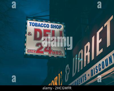 Tobacco shop and deli sign at night, in The Bronxs Little Italy, New York  City Stock Photo