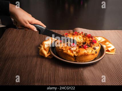 Woman's hand cutting a roscon de reyes with a knife Stock Photo
