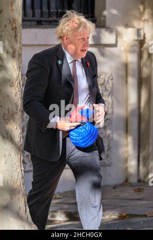 British Prime Minister Boris Johnson holds his son Wilfred's jacket as he walks in Westminster, London, UK Stock Photo