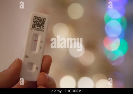 London, UK, 29 December 2021: A negative lateral flow test, seen in front of Christmas fairy lights, clears the owner to go out and meet with friends. Stock Photo