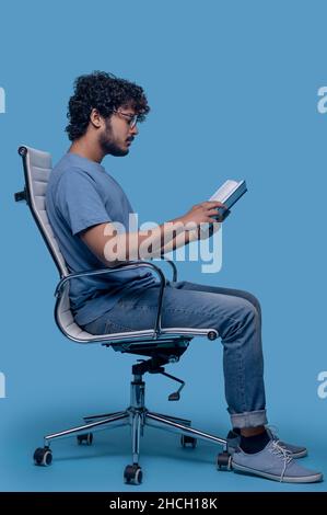 Concentrated guy in eyeglasses perusing his diary entries Stock Photo