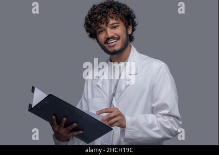 Cheerful doctor with documents in his hands looking ahead Stock Photo