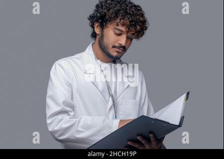 Concentrated physician holding documents in his hands Stock Photo