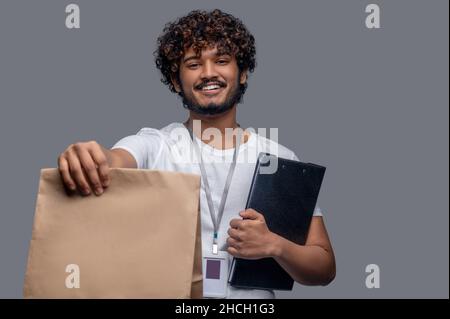 Pleased deliveryman posing for the camera against the gray background Stock Photo