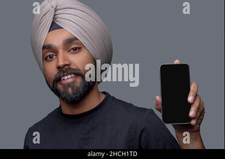 Pleased bearded mustached Indian man showing his gadget Stock Photo