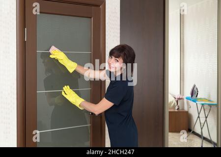 Smiling Professional Female Cleaners Washing Apartment With Rags