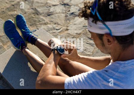 Young caucasian man checking pulse on a smartwatch in an outdoor park while is doing exercise Stock Photo