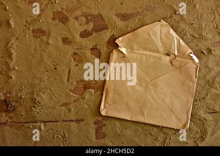 Crumpled letter envelope on wooden board with sandy background Stock Photo