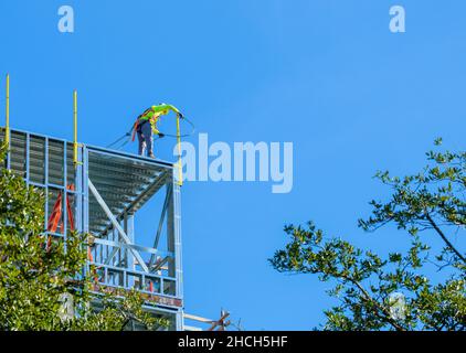 Unidentified construction worker on side of new building attaching a safety cable to a steel bar on December 23, 2021 in New Orleans, LA, USA Stock Photo