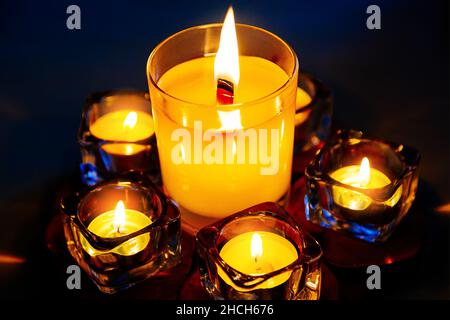 Memorial candles burn in dark. Mourning ritual and mourning for dead. Candles in candlesticks close-up. Background Stock Photo