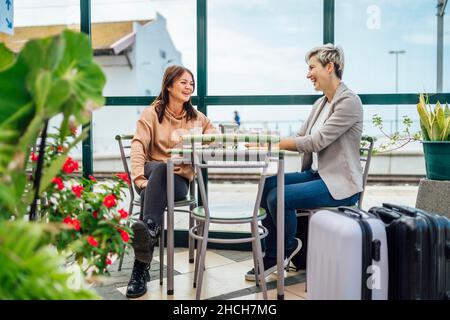 Two travelling women with luggage drinking coffee at train station, Portugal Stock Photo