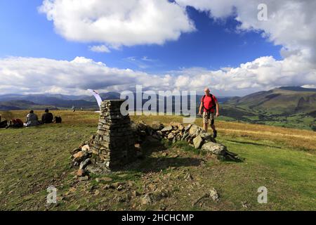 Walker at the summit cairn on Clough Head fell above St Johns in the Vale village, near Keswick, Lake District National Park, Cumbria, England, UK Clo Stock Photo