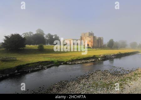 Misty view of the Ruins of Brougham Castle, river Eamont, near Penrith, Cumbria County, England, UK Stock Photo