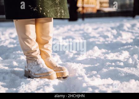 Cropped image of women's winter white shoes in the snow. Warm comfortable waterproof boots. Footwear for winter. Copyspace. Stock Photo