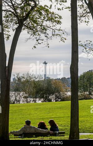 Three people on a bench in Gas Works park viewing Lake Union and the Space Needle in Seattle, Washington. Stock Photo
