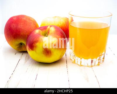 Closeup shot of three apples and apple juice on the wooden table Stock Photo