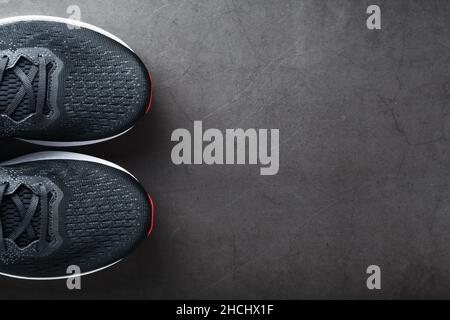 Black running shoes with mesh and black laces close-up on a dark background. Top view of sports sneakers. Stock Photo