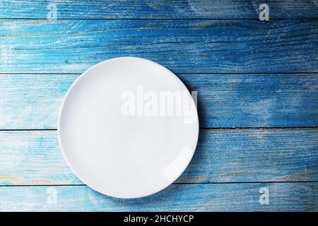 Empty round bowl on a blue wooden background from above. Free space Stock Photo