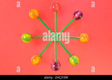 Tasty lollipops on coral pastel color background. Set of realistic colorful lollipops on green plastic sticks. Summer and pop art concept. Top view. R Stock Photo