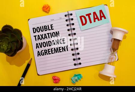 Closeup on businessman holding card with DTAA DOUBLE TAXATION AVOIDANCE AGREEMENT acronym text, business concept image with soft focus background and Stock Photo