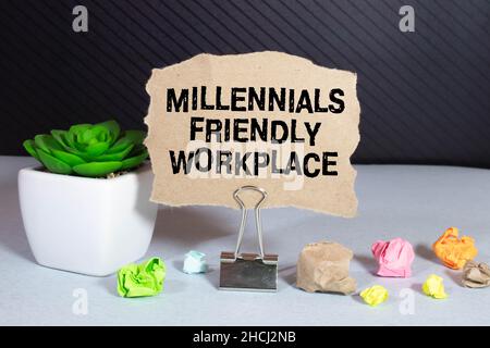 Closeup on businessman holding a card with text MILLENNIALS FRIENDLY WORKPLACE , business concept image with soft focus background and vintage tone Stock Photo