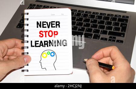 Never Stop Learning, handwriting quotation on notebook with light bulbs. Stock Photo