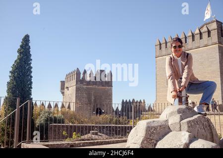 Young smiling Hispanic female traveler holding a sword in the famous old Castle of Almodovar del Rio Stock Photo