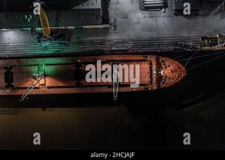 Ship Offloading Cargo at Docks at Night Stock Photo